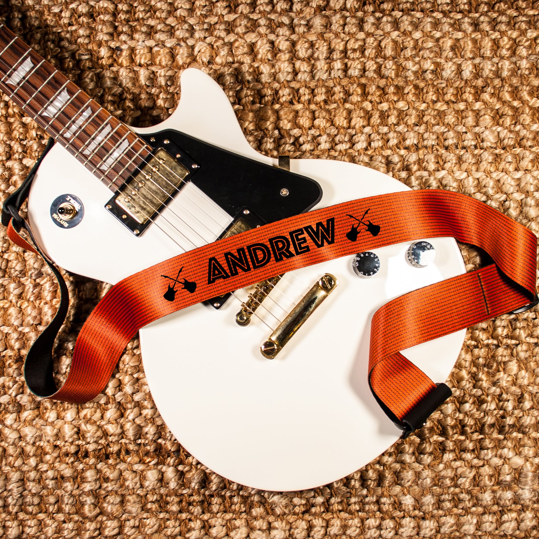 Orange polyester guitar strap on a white guitar. 