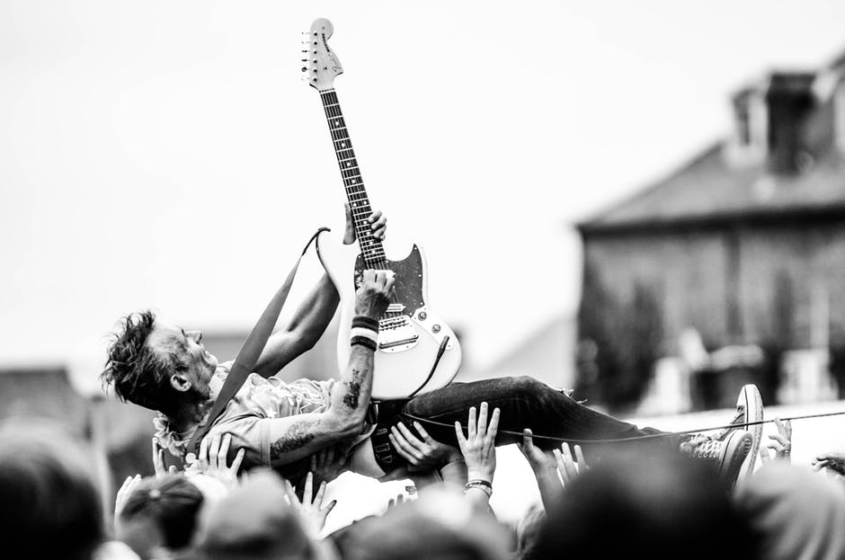 Crowd surfing while playing the guitar.