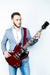A guy wearing a red guitar and guitar strap. 
