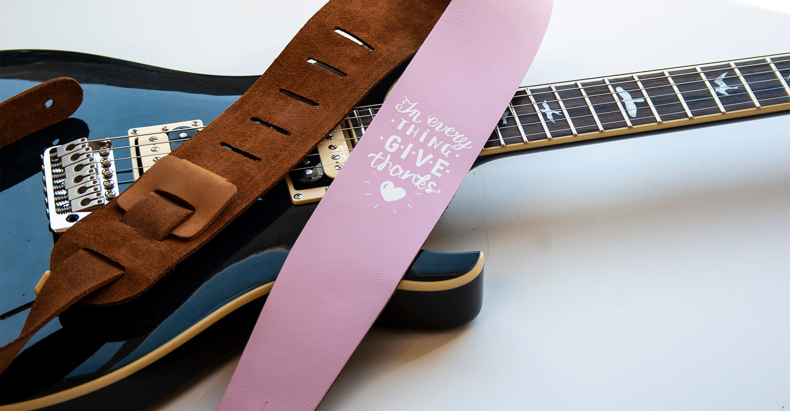 Pink guitar strap laying carefully on a guitar. 