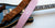 Pink guitar strap laying carefully on a guitar. 