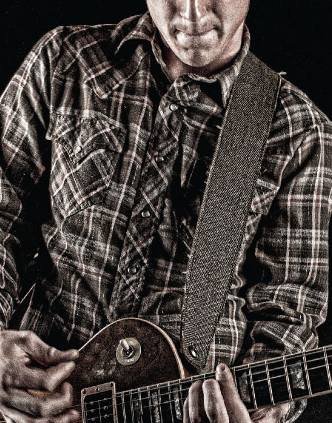 Guitar Player playing a electric guitar with a leather guitar strap.