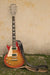 Guitar with a strap against a wall.