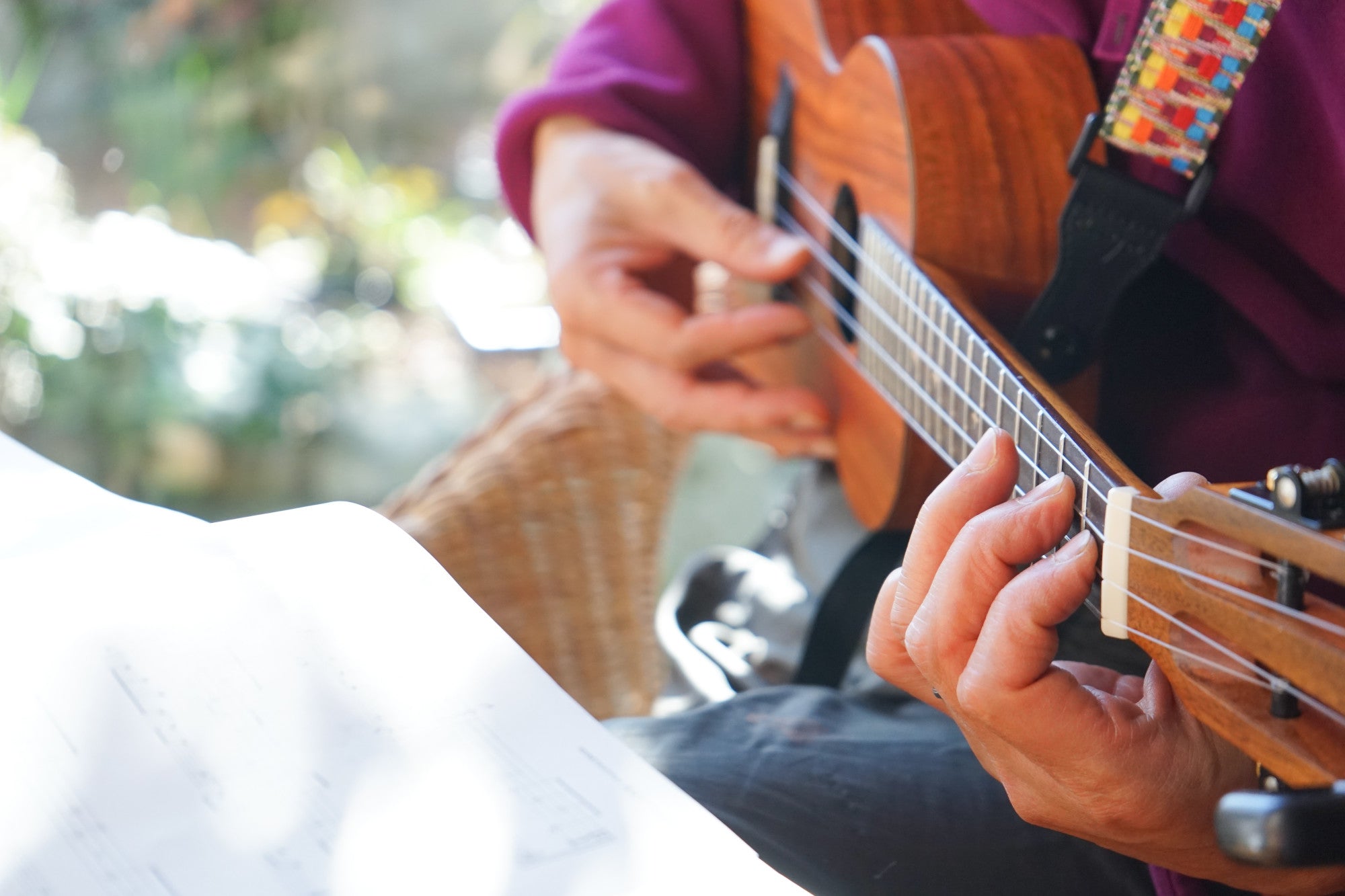 A person playing a ukulele with a strap.